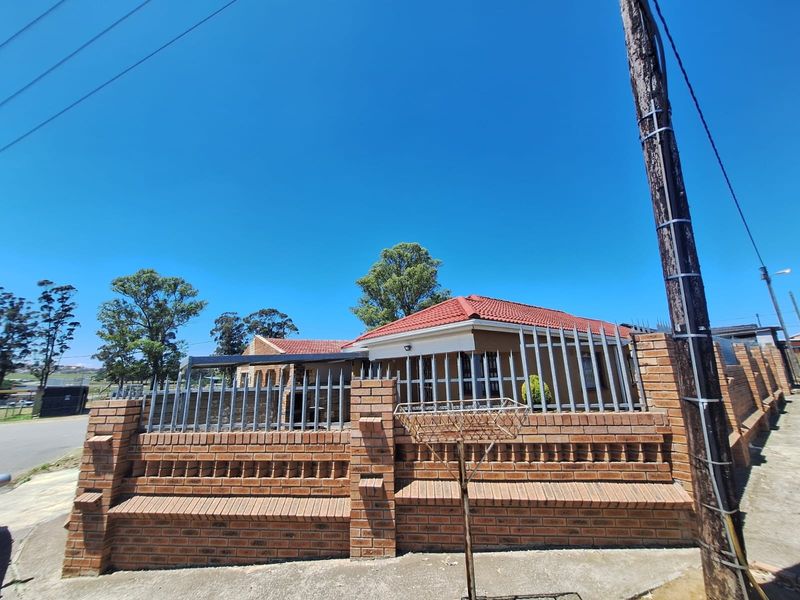 Front exterior view of a residential house featuring a brick boundary wall with integrated metal security fencing and a tiled roof.