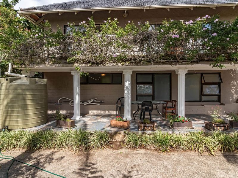 A covered ground-floor patio featuring decorative columns, tiled flooring, and direct access to the garden, complemented by an integrated water storage tank.