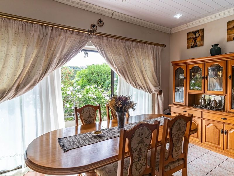A dining room featuring tiled flooring, crown molding, and a large sliding glass door that provides natural light and garden views.