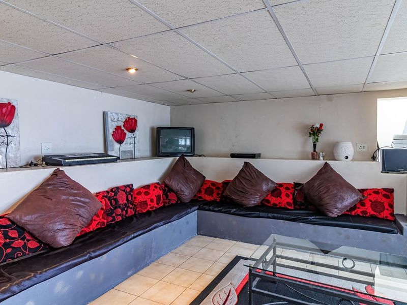 A living area featuring built-in seating, tiled flooring, and a suspended ceiling with recessed lighting.