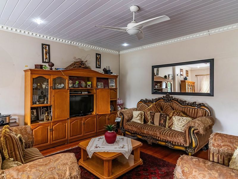A living room featuring a timber-look ceiling with decorative cornice, a central ceiling fan, and recessed downlighting.