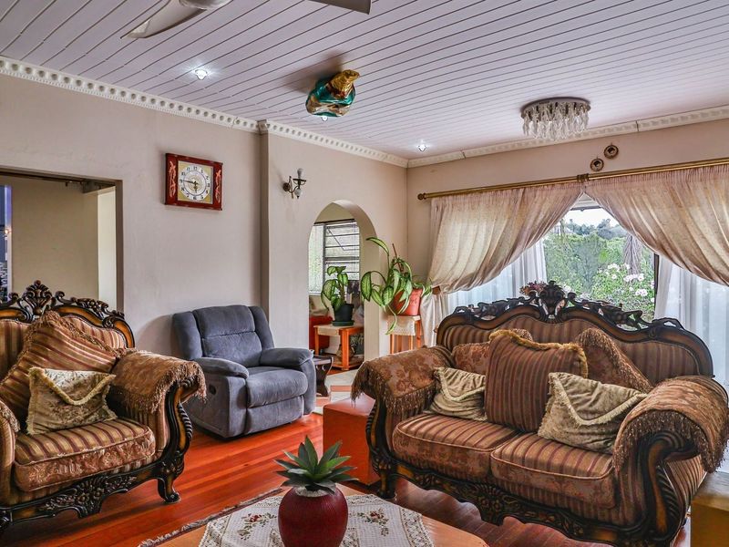 A traditional living room featuring hardwood flooring, a tongue and groove ceiling, and an arched entryway leading to adjacent living spaces.
