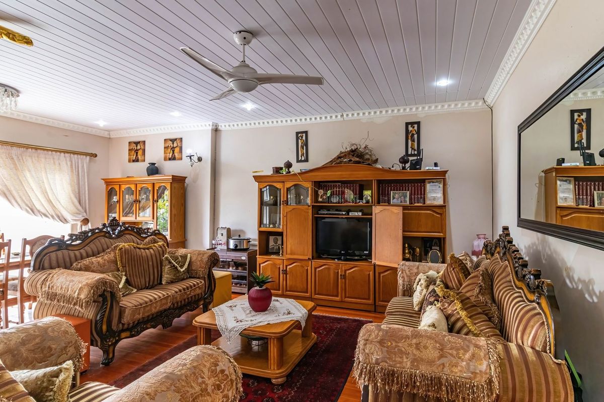 Spacious living room featuring timber flooring, a tongue and groove ceiling with recessed lighting, and crown molding details.