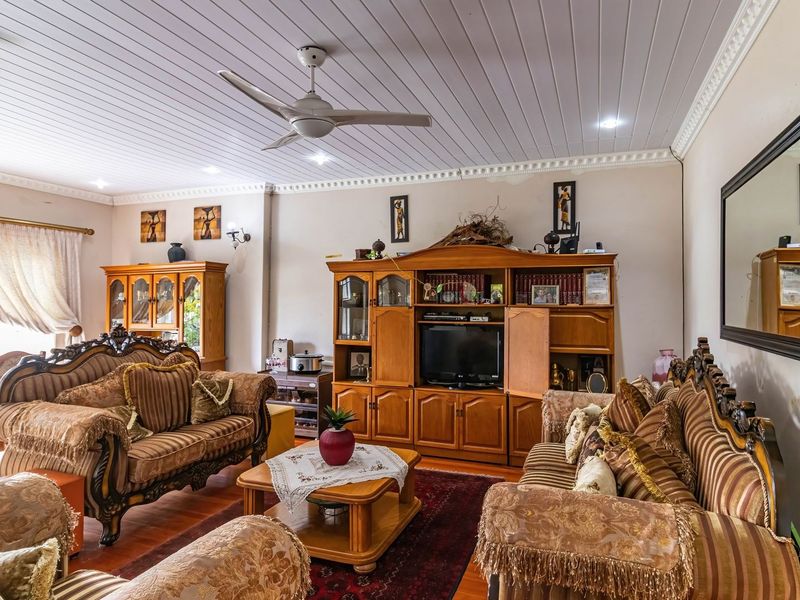 Spacious living room featuring timber flooring, a tongue and groove ceiling with recessed lighting, and crown molding details.