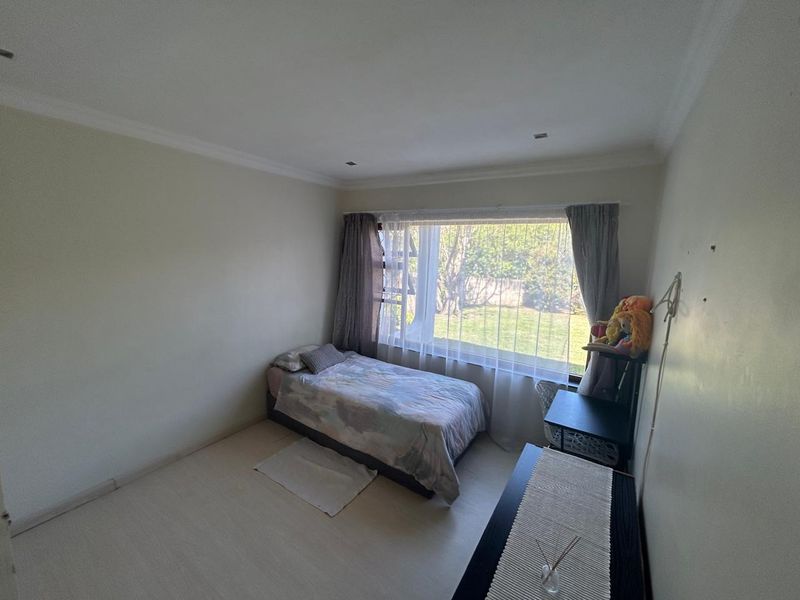 A functional bedroom featuring a large window with garden views, recessed downlighting, and coved ceiling finishes.