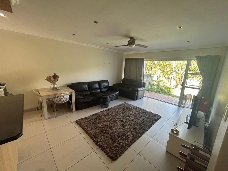 Open-plan living area featuring tiled flooring, recessed lighting, a ceiling fan, and large sliding glass doors providing access to the rear garden.