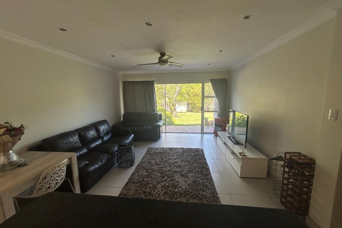 Spacious living room featuring tiled flooring, recessed lighting, and a ceiling fan, with direct access to the rear garden through a sliding glass door.