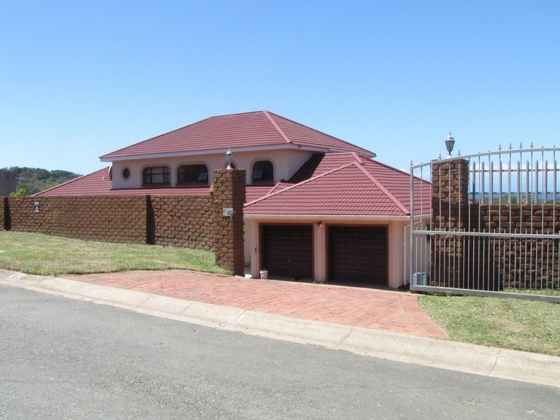Front view of a residential property featuring a double garage, brick boundary wall, metal gate, and a tiled roof.