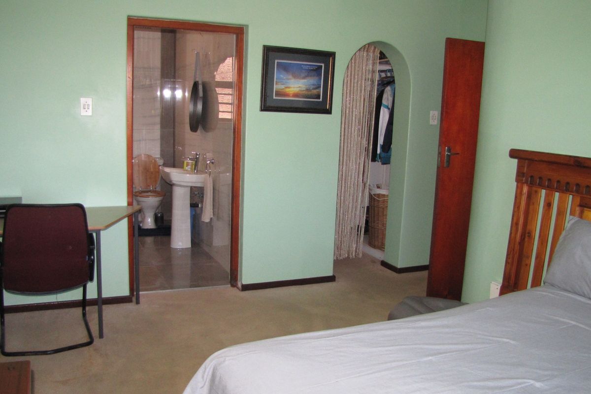 Bedroom featuring an en-suite bathroom, walk-in closet access via an archway, and carpeted flooring.