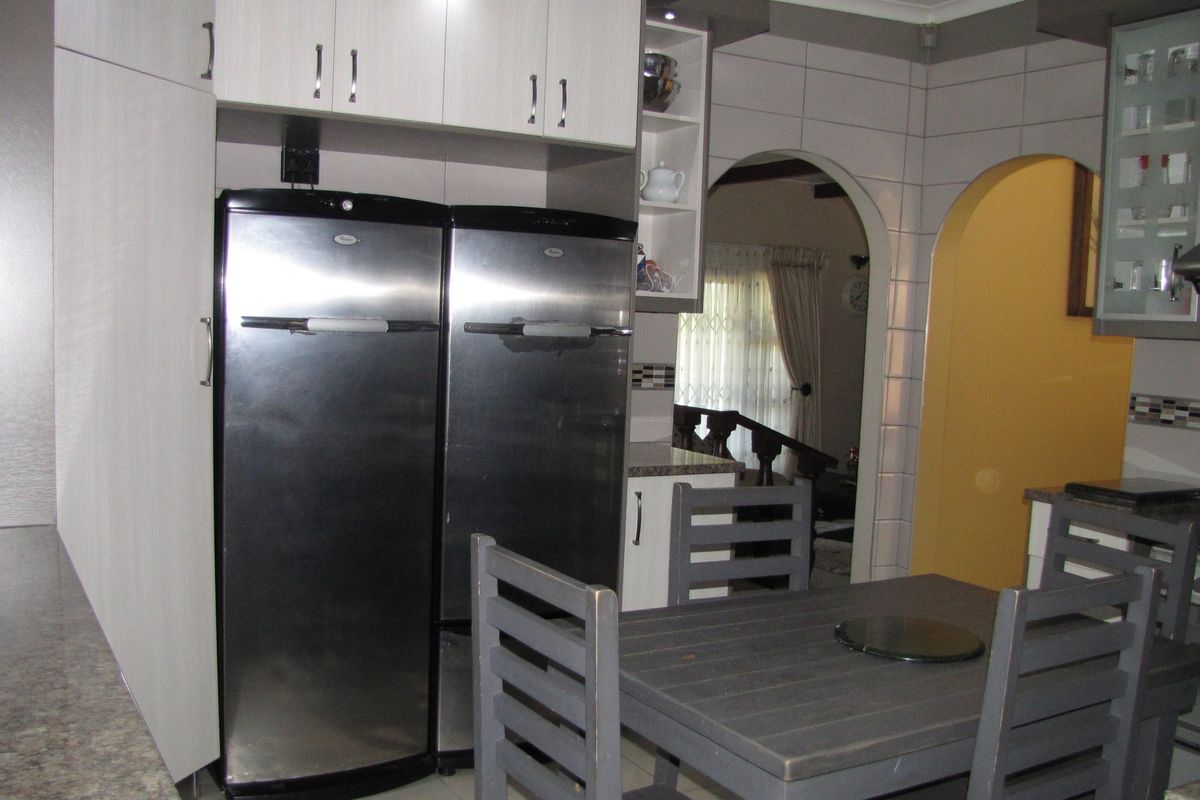 A functional kitchen featuring built-in cabinetry, a gas hob with extractor fan, and distinctive arched doorways leading to adjacent living spaces.