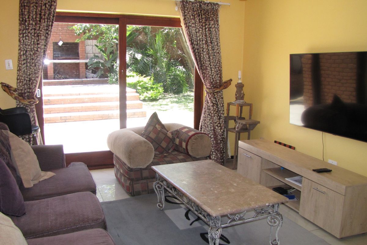 A living room featuring tiled flooring and a large sliding glass door providing direct access to the rear patio and garden area.