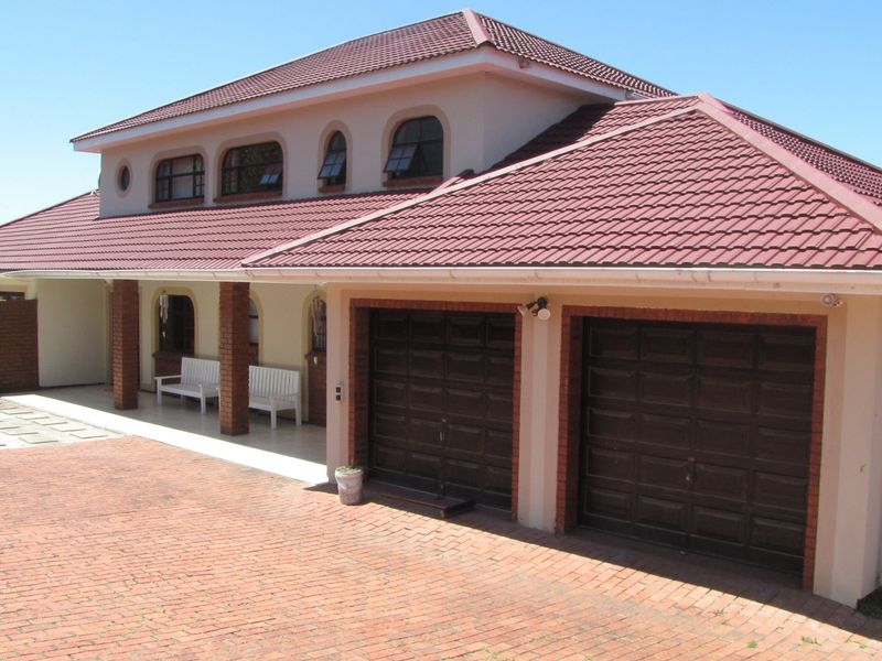 A well-maintained double-story house featuring a double garage, tiled roof, and a spacious covered patio area with brick detailing.