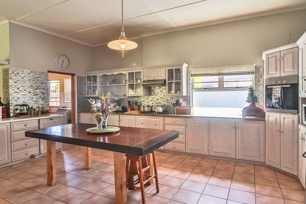 Spacious kitchen featuring extensive built-in cabinetry, a mosaic tile backsplash, tiled flooring, and a built-in oven with an extractor fan.