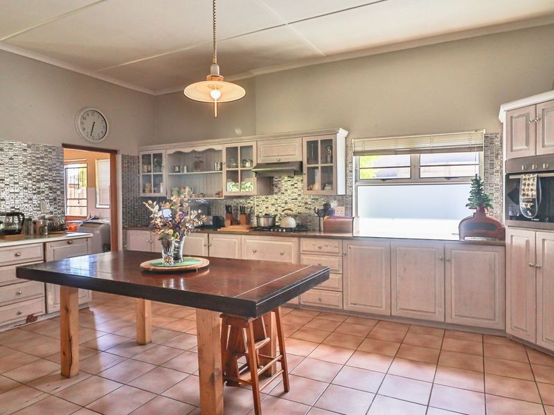 Spacious kitchen featuring extensive built-in cabinetry, a mosaic tile backsplash, tiled flooring, and a built-in oven with an extractor fan.