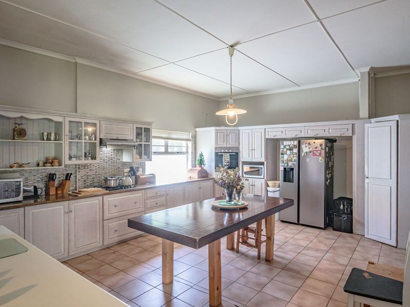 Spacious kitchen featuring extensive built-in cabinetry, mosaic tile backsplash, tiled flooring, and a central island, offering a functional layout with ample storage.