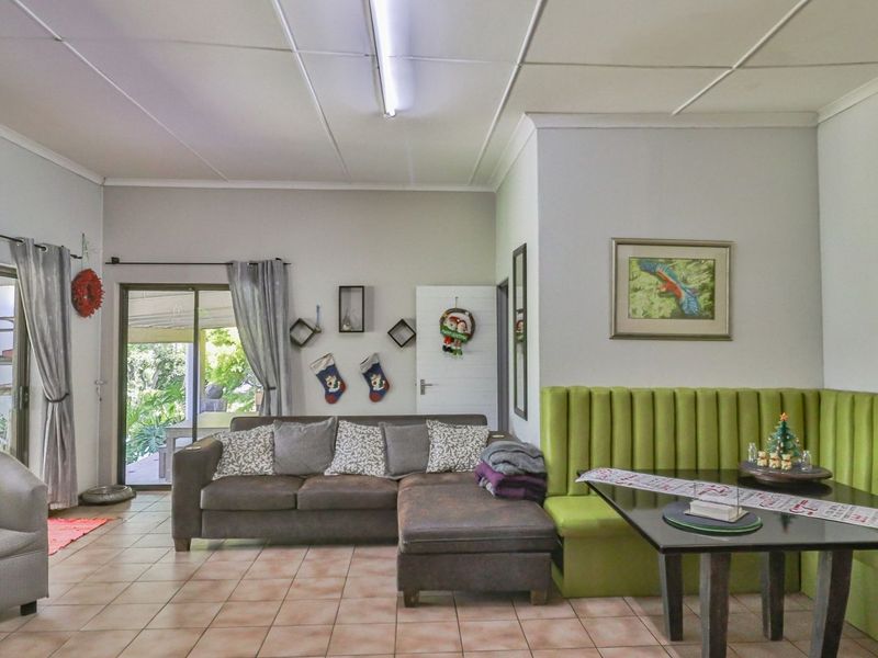 Open-plan living and dining area featuring tiled flooring, built-in bench seating, and sliding glass doors providing access to the outdoor patio.