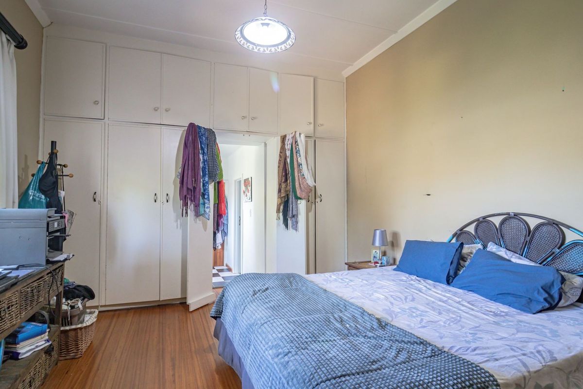 Bedroom featuring extensive built-in cupboard storage, laminate flooring, and a central ceiling light fixture.