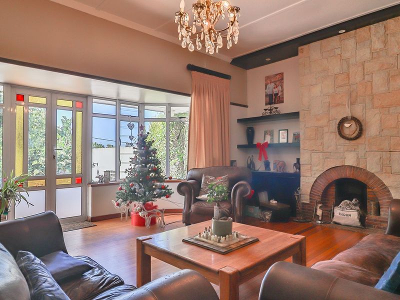 Spacious living room featuring a prominent stone fireplace, hardwood flooring, and a large bay window that provides ample natural light.