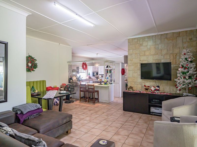 Spacious open-plan living and kitchen area featuring a stone accent wall, tiled flooring, and a functional kitchen island layout.