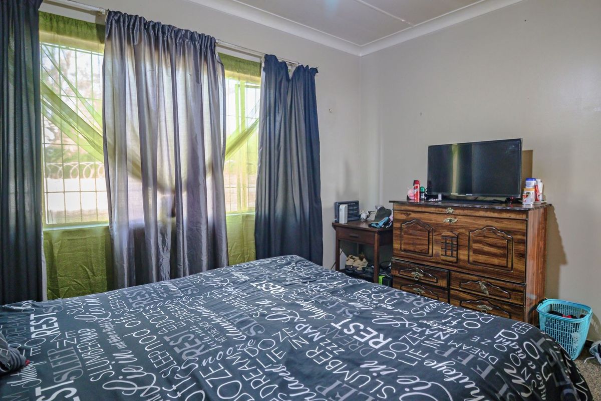 A standard bedroom featuring security bars on the windows and decorative ceiling coving.