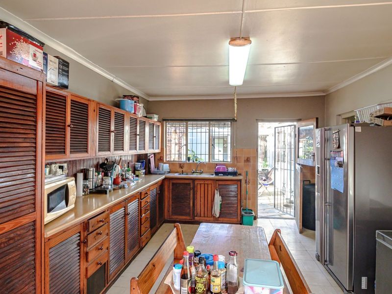A functional kitchen featuring extensive wooden cabinetry, laminate countertops, and direct access to an outdoor area through a security gate.