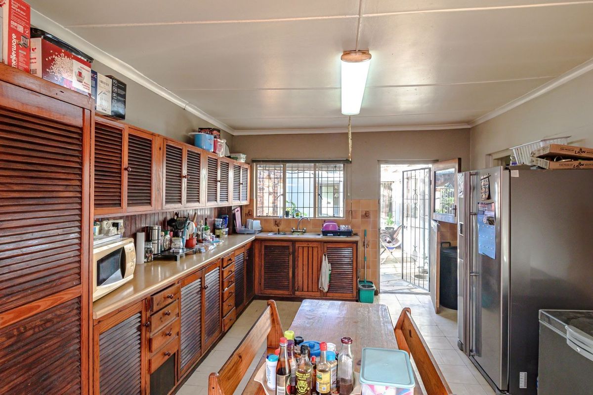 A functional kitchen featuring extensive wooden cabinetry, laminate countertops, and direct access to an outdoor area through a security gate.