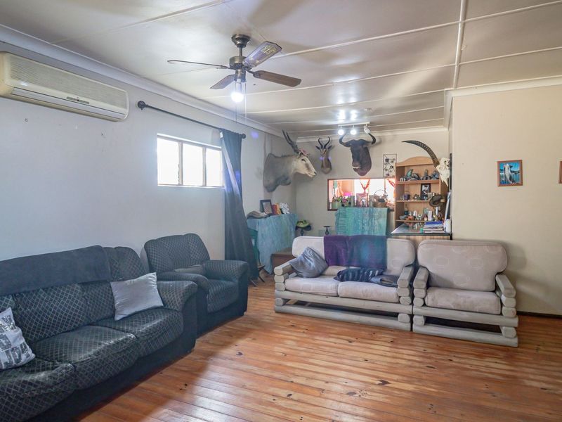 A living room featuring timber flooring, a ceiling fan, and a wall-mounted split-system air conditioner.