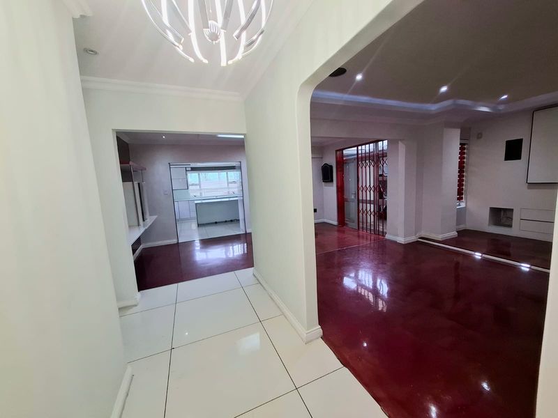 Spacious open-plan living area featuring a mix of tiled and polished concrete flooring, recessed lighting, and a built-in fireplace with a security gate.