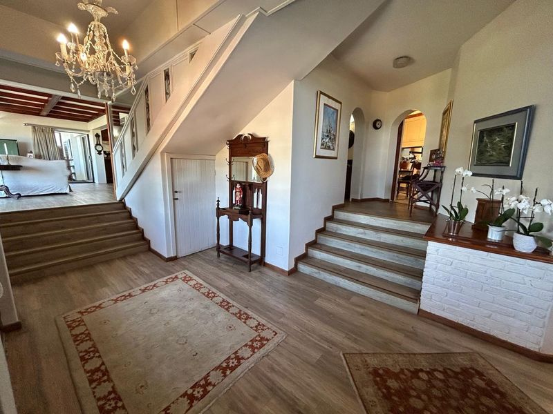 Spacious entrance hall featuring timber flooring, a central staircase, and charming archways leading to adjacent living areas.