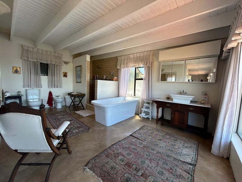 Spacious bathroom featuring a freestanding bathtub, vessel sink vanity, bidet, and toilet, complemented by exposed beam ceilings and neutral finishes.