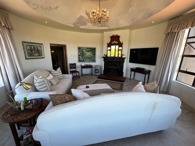 A spacious living room featuring a unique domed ceiling with a mural, a traditional fireplace with a mantelpiece, and recessed lighting.