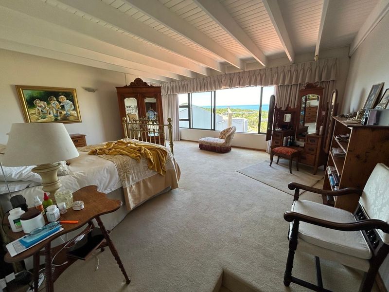 Spacious bedroom featuring exposed beam ceilings and a large picture window with scenic coastal views.