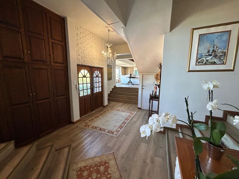 Spacious entrance hall featuring timber flooring, built-in cabinetry, an exposed brick feature wall, and a grand staircase leading to the upper level.