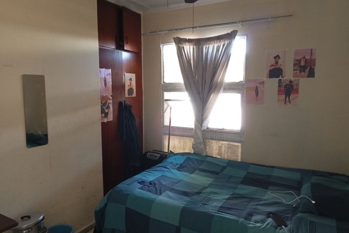A bedroom featuring a built-in cupboard, tiled flooring, and a ceiling fan, requiring cosmetic updates to improve its overall appeal.