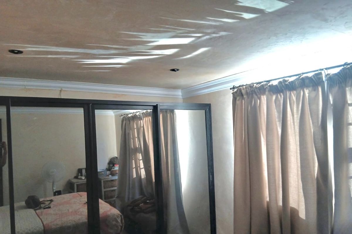Bedroom featuring a large built-in sliding door wardrobe with mirrored panels, recessed ceiling lighting, and decorative cornice molding.