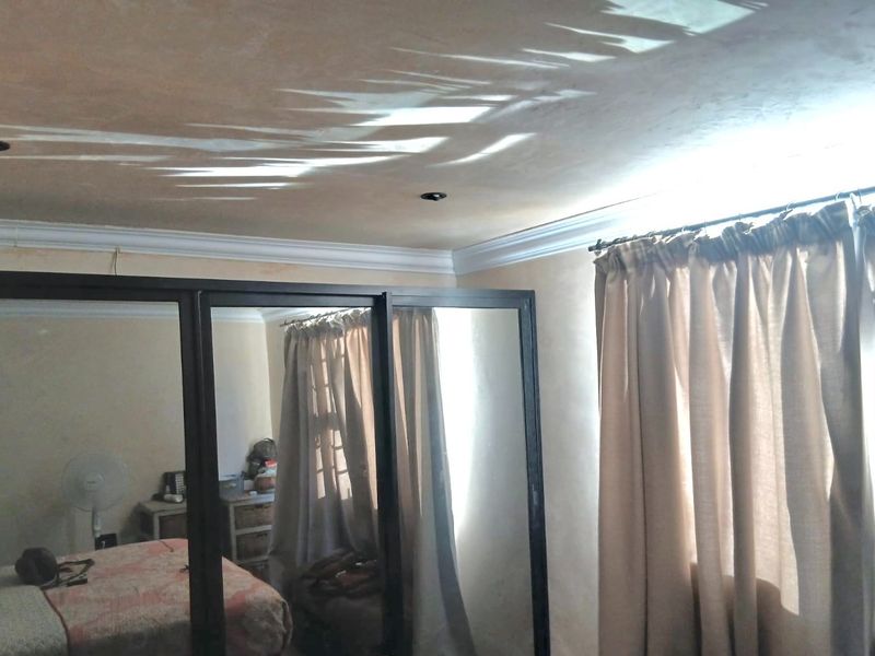 Bedroom featuring a large built-in sliding door wardrobe with mirrored panels, recessed ceiling lighting, and decorative cornice molding.