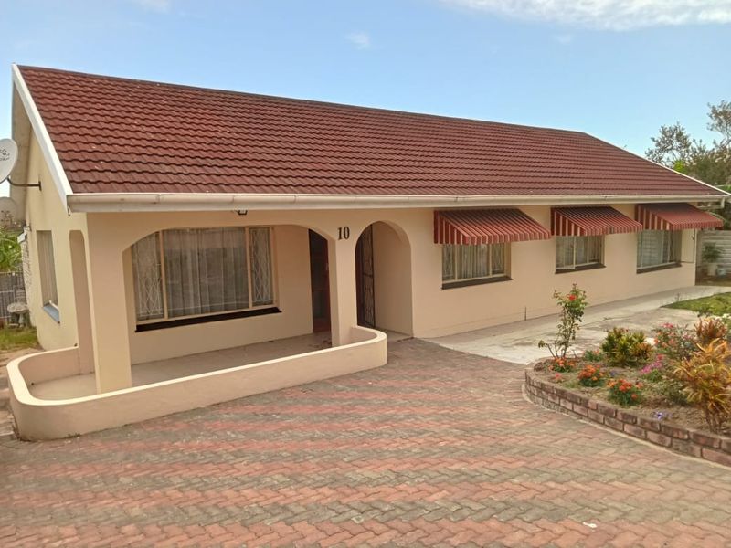 Front view of a single-story house featuring a tiled roof, paved driveway, and a covered porch entrance.