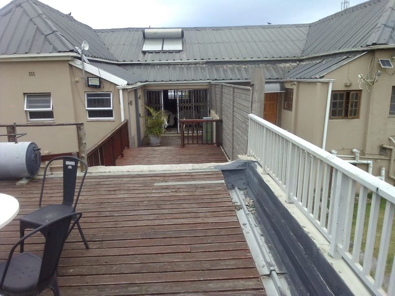 An elevated timber deck patio area featuring a metal balustrade, providing access to the rear building elevation with solar water heating infrastructure.