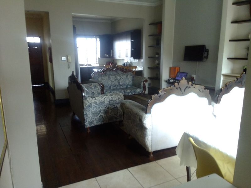 Open plan living area featuring dark wood flooring, built-in shelving, and a view through to the kitchen area.
