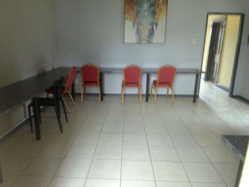 A functional living area featuring tiled flooring and a long built-in desk surface, providing a versatile space for work or study.