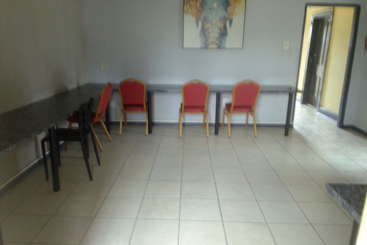 A functional living area featuring tiled flooring and a long built-in desk surface, providing a versatile space for work or study.
