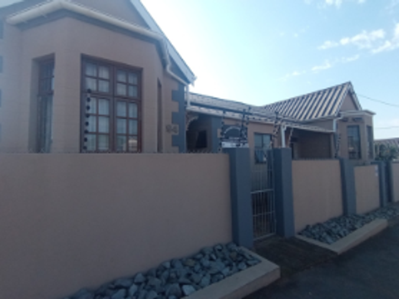 Front exterior view of a residential house featuring a perimeter wall, electric fencing, metal gate, and tiled roof with bay windows.