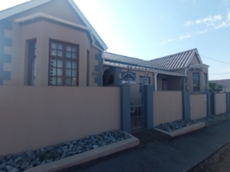 Front elevation of a residential house featuring a perimeter wall with electric fencing, tiled roof, and timber-framed windows.