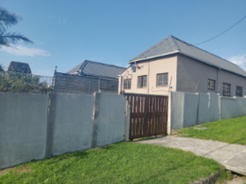 Front exterior view of the property featuring a concrete boundary wall, timber gate, electric fencing, and a pitched metal roof.