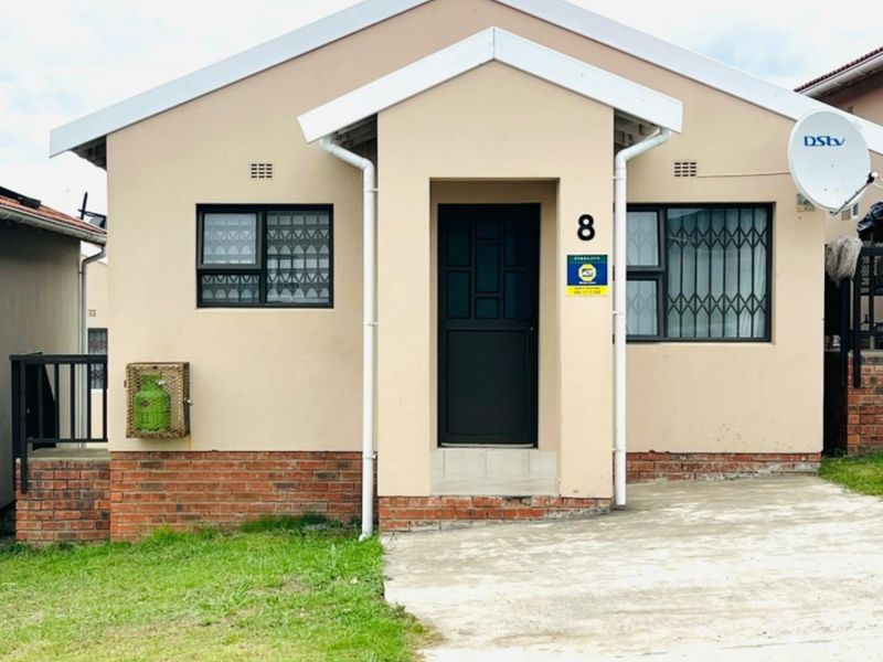 A well-maintained single-story residential home featuring a brick base, concrete driveway, and secure window bars.