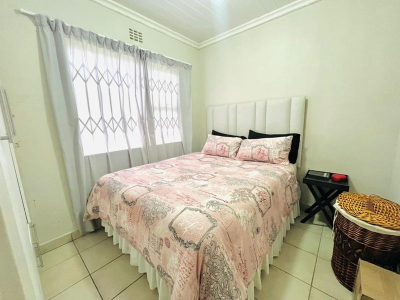 A functional bedroom featuring tiled flooring, a built-in cupboard, and a security gate on the window.