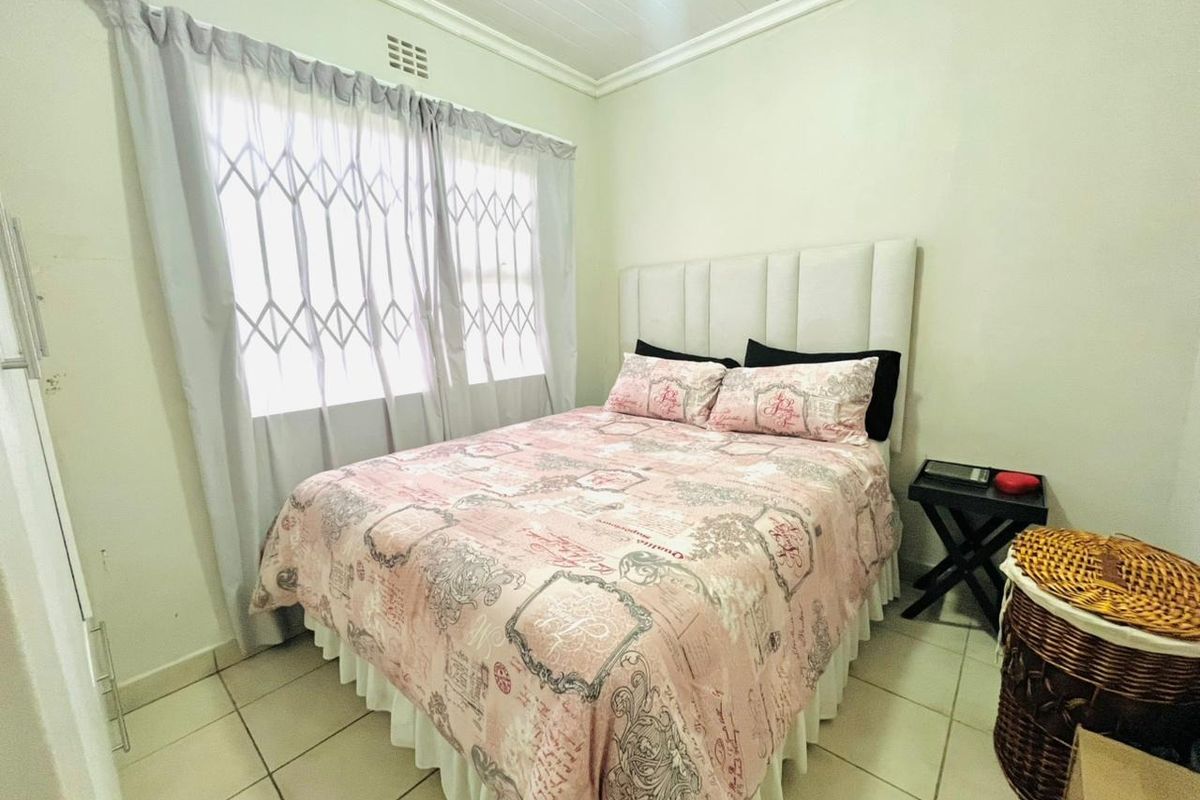 A functional bedroom featuring tiled flooring, a built-in cupboard, and a security gate on the window.