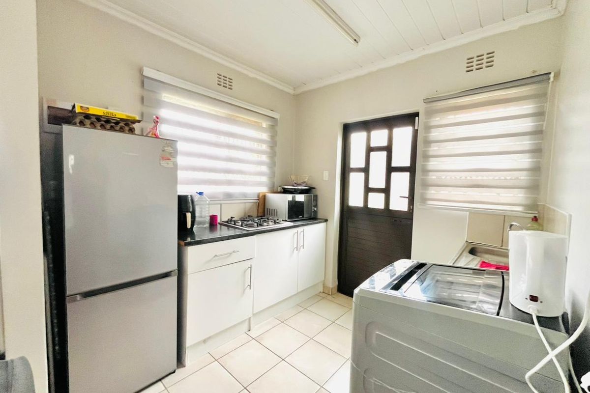 Functional kitchen featuring built-in cabinetry, a gas hob, tiled flooring, and direct access to the exterior via a paneled door.