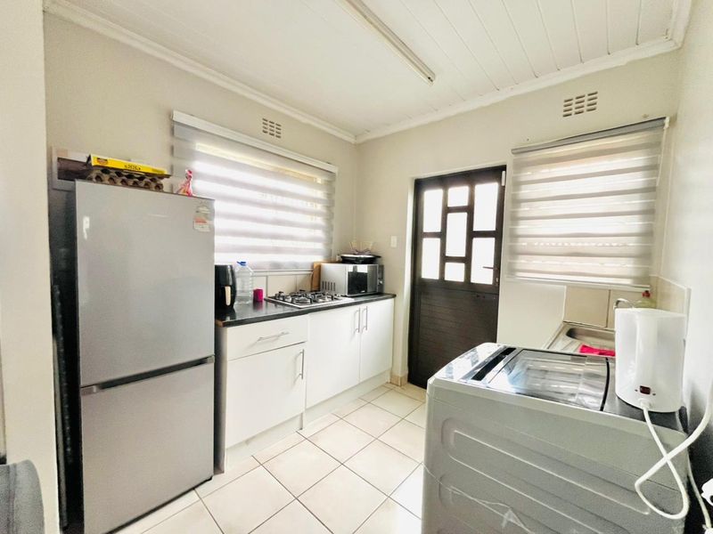 Functional kitchen featuring built-in cabinetry, a gas hob, tiled flooring, and direct access to the exterior via a paneled door.