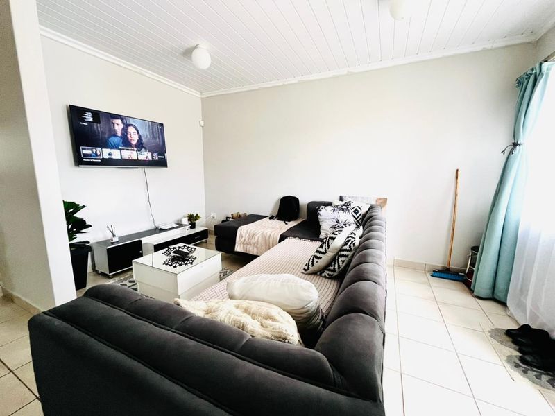 A comfortable living room featuring tiled flooring and a classic tongue and groove ceiling, providing a functional and inviting space for relaxation.